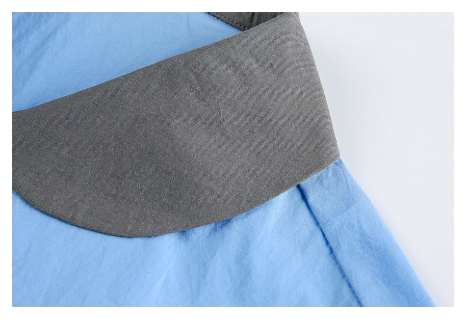 Close-up of the broad charcoal gray collar against the light blue shirt fabric.