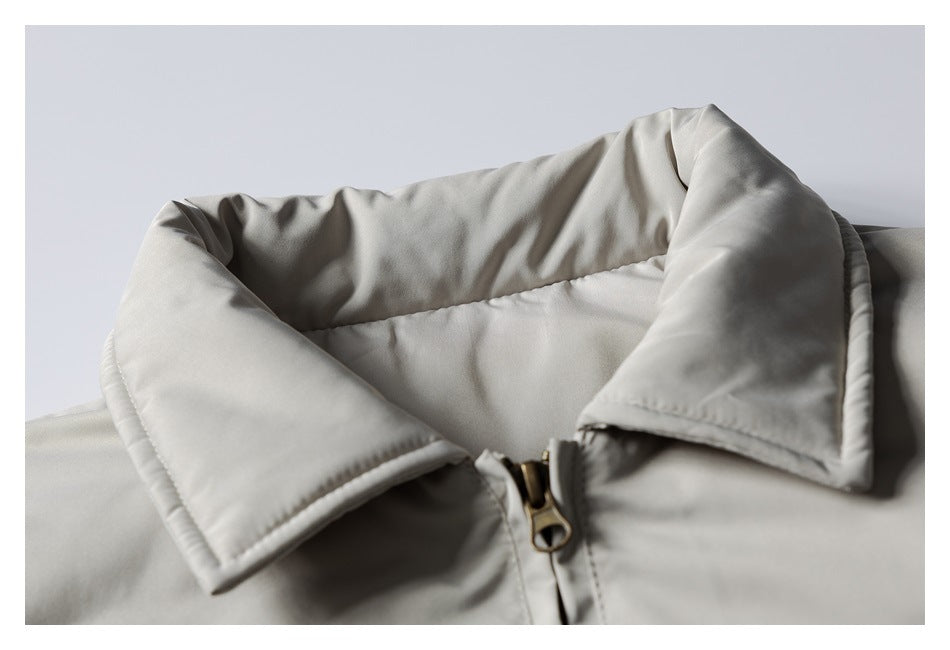 Close-up of a light gray jacket's padded collar and brass-tone front zipper.