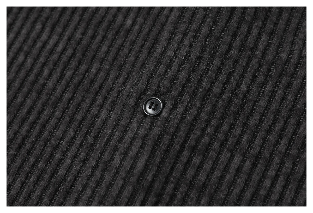 Close-up of a dark button against the shirt's textured charcoal ribbed fabric.