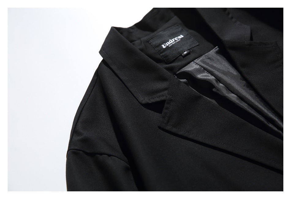 Close-up of a black blazer's notched lapel, satin lining, and inner neck label.