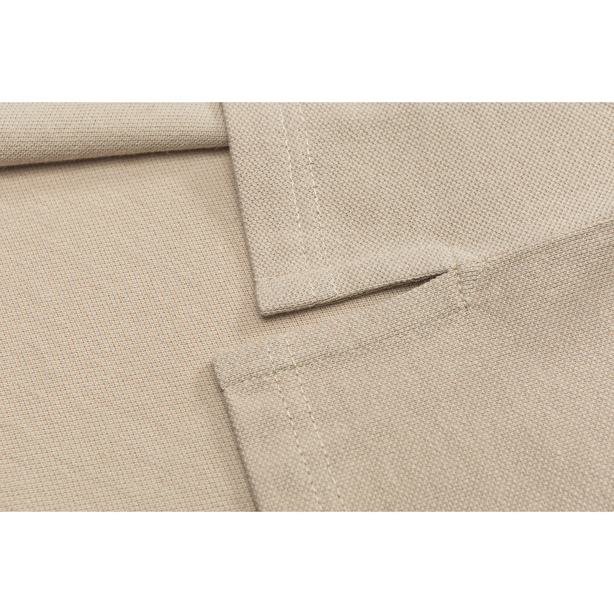 Close-up of beige polo shirt fabric showing a stitched seam and overlapping fabric edges.
