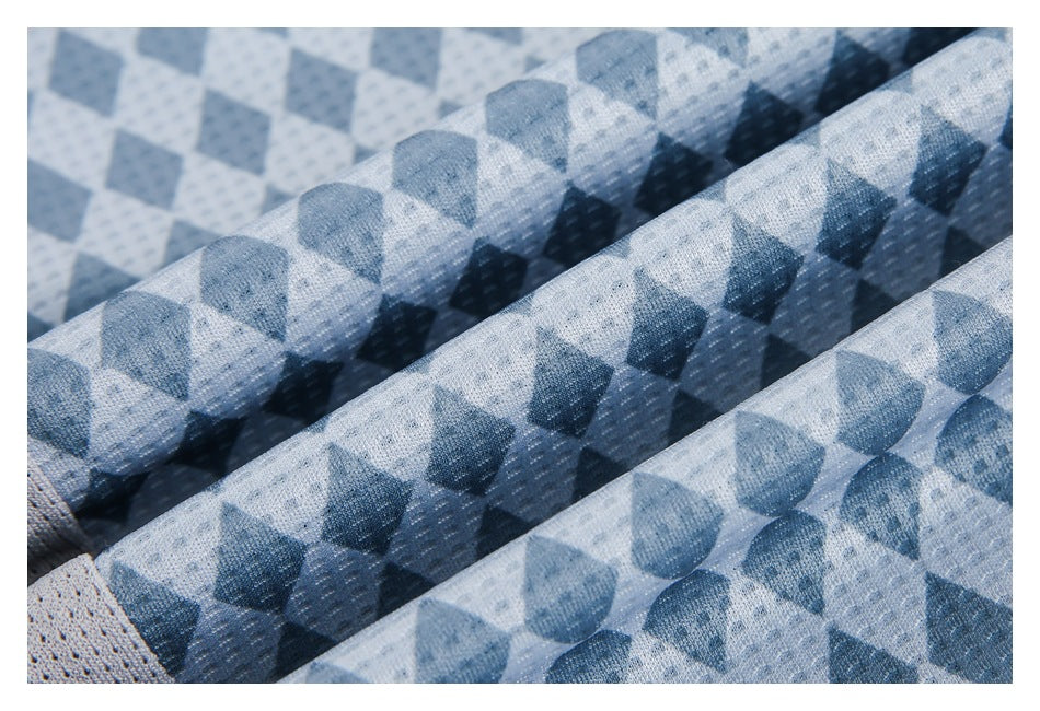Close-up of folded blue geometric-print fabric showing its textured surface and a light gray mesh section.