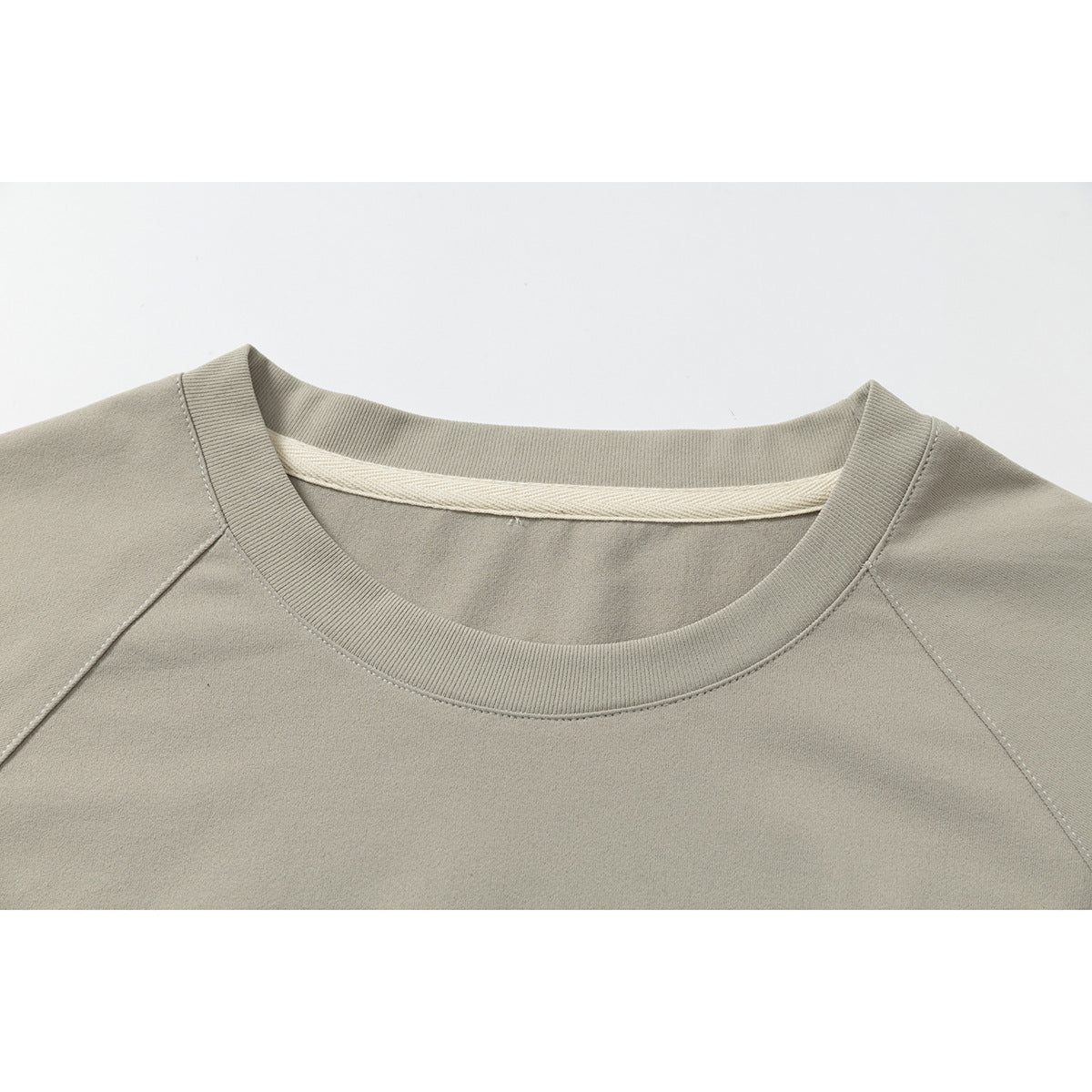 Close-up of a taupe crew neckline with ribbed trim and raglan shoulder seams.