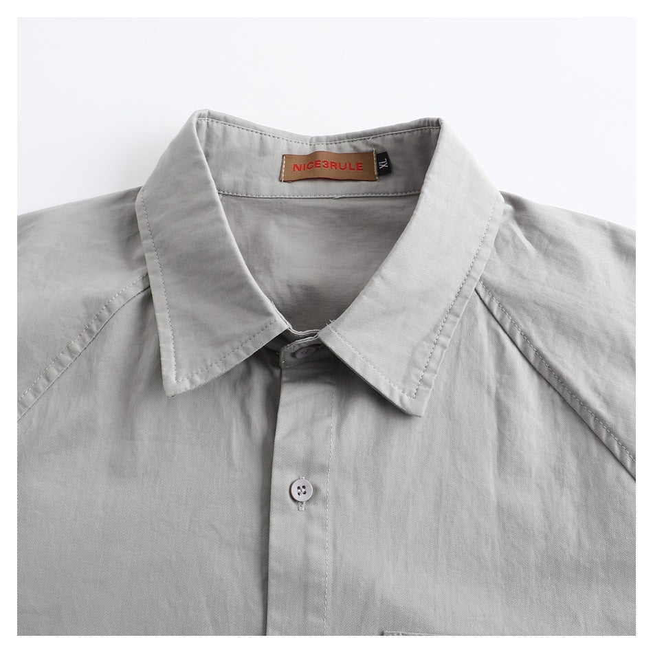 Close-up of a light gray shirt collar, button placket, and sewn-in neck label.