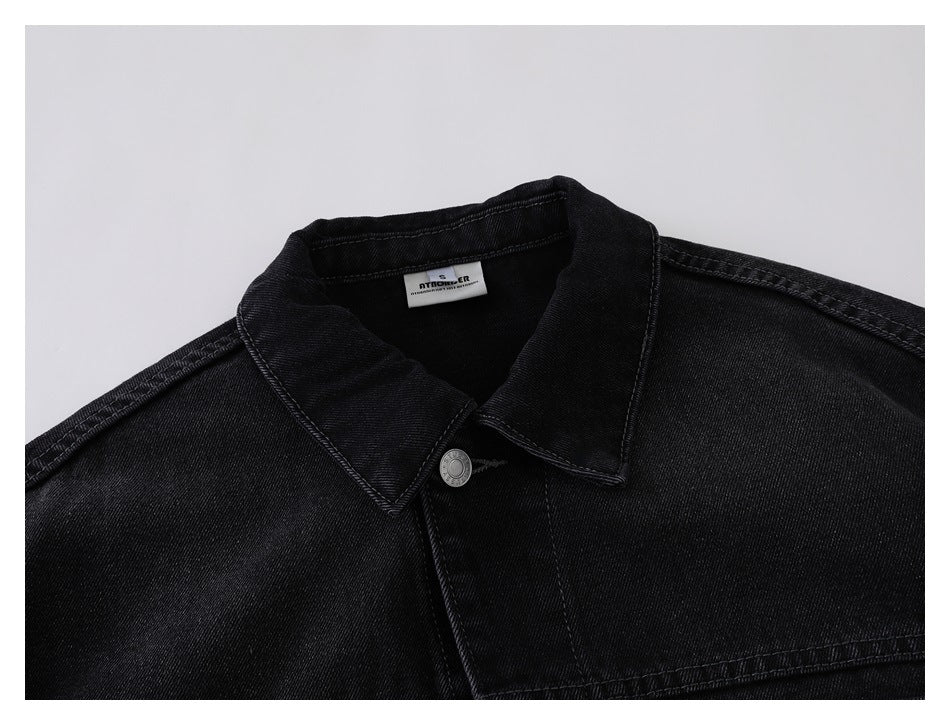 Close-up of the black denim jacket collar, upper front, silver button, and inner neck label.