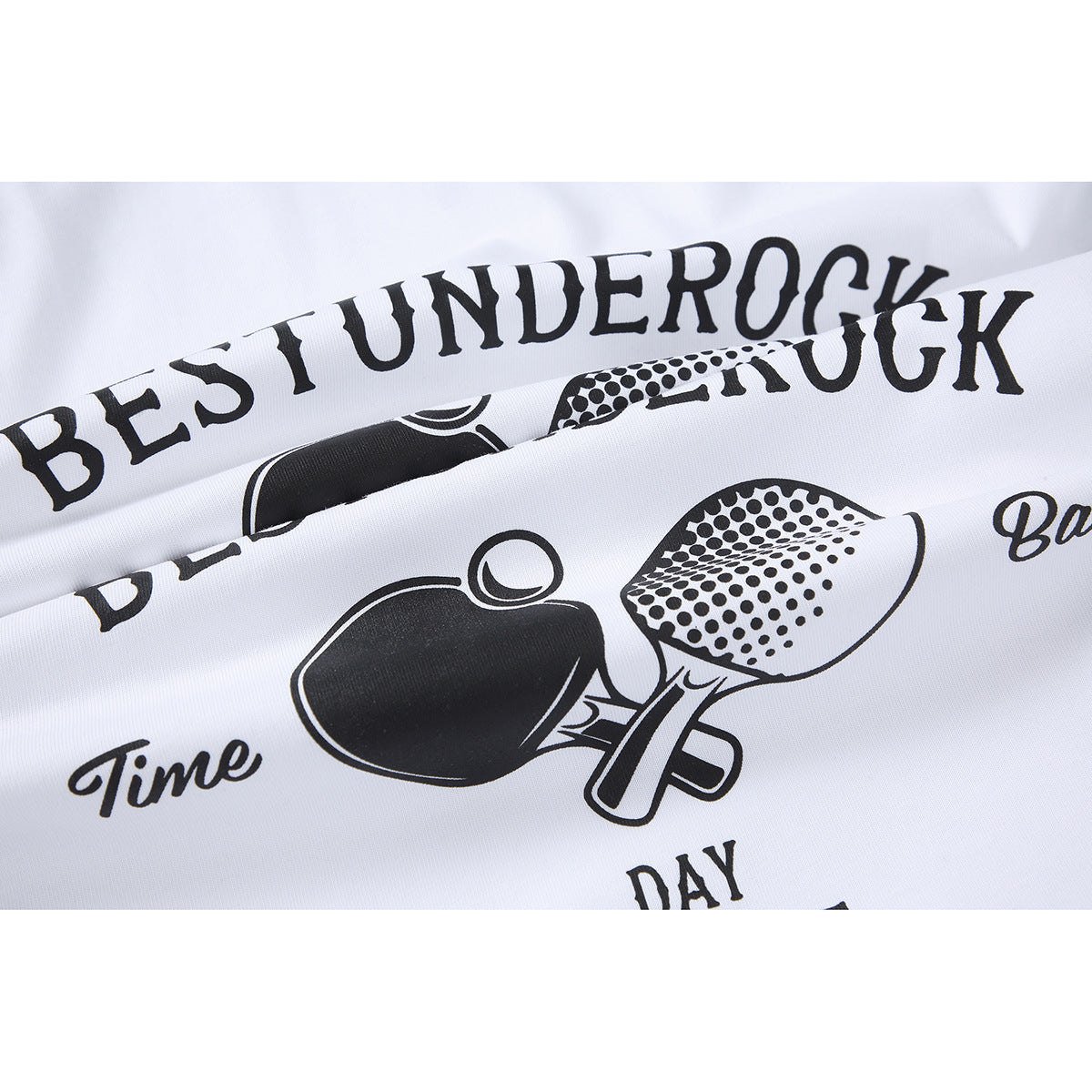 Close-up of the black ping-pong paddle graphic and English lettering printed on white T-shirt fabric.