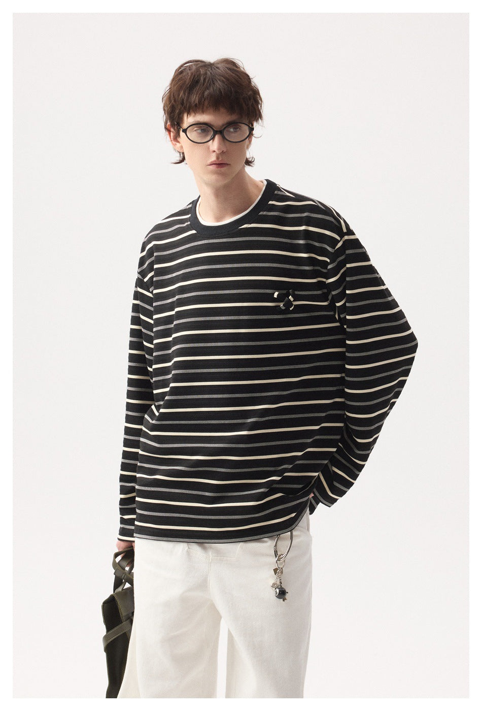 Model wearing a black long-sleeve shirt with cream and gray horizontal stripes and a small chest embellishment.