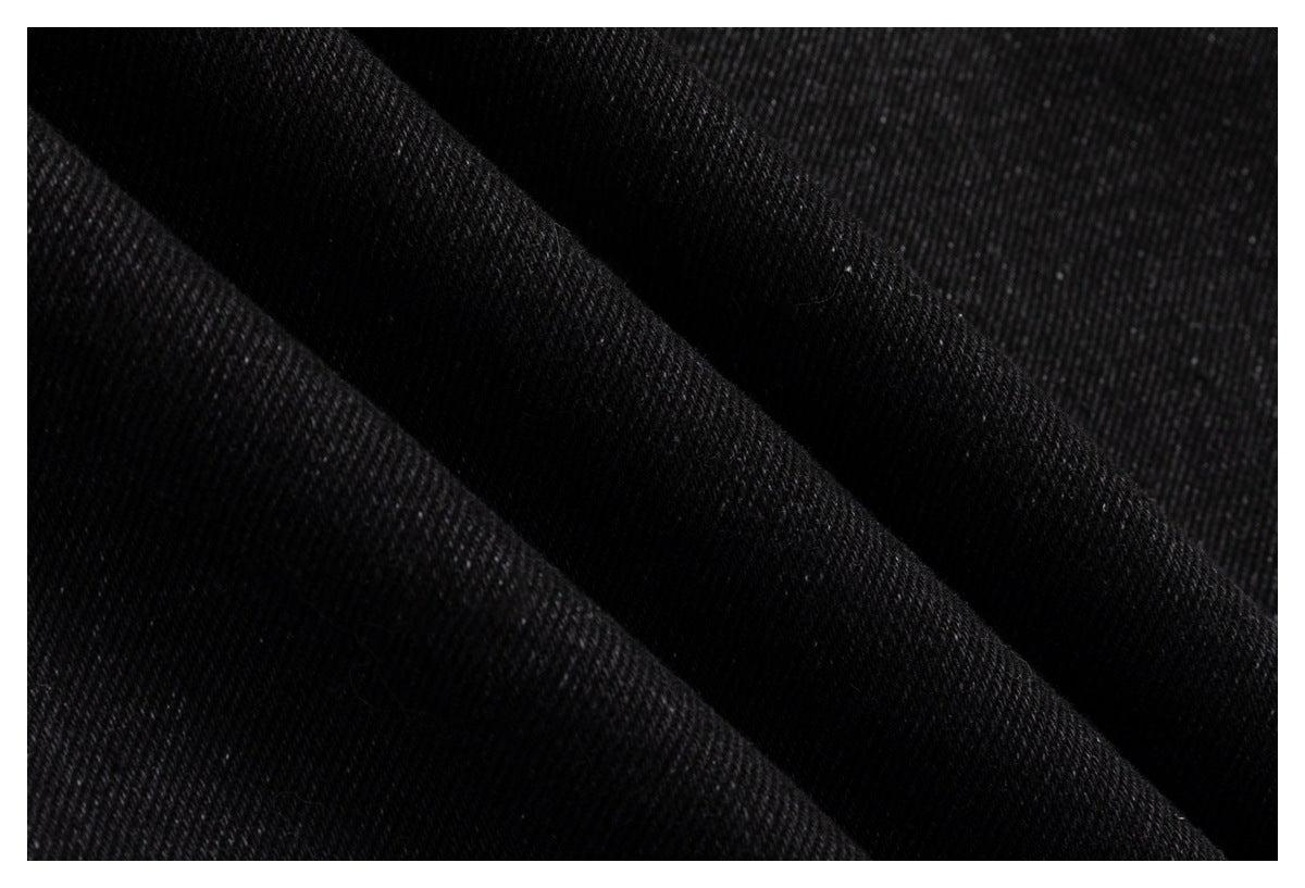Close-up of black fabric folded into diagonal ridges, showing a fine woven texture.