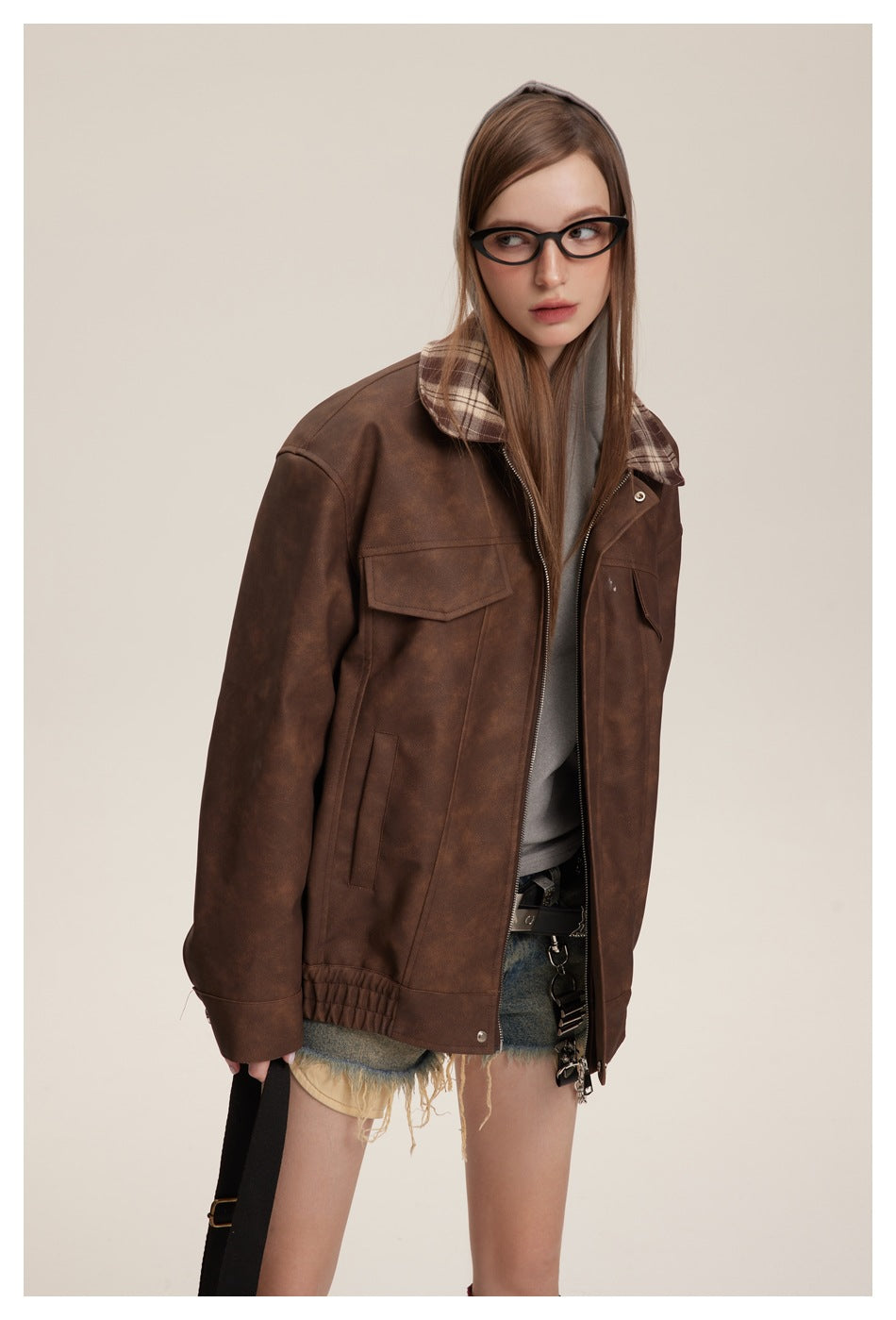 Model in a brown zip-front jacket with plaid collar and flap pockets, shown from the thighs up.