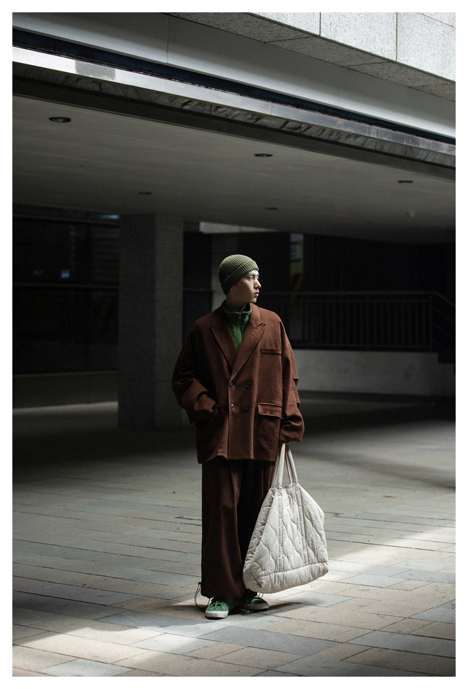 Full-length model wearing a brown blazer and wide-leg trousers with a green top and olive beanie.