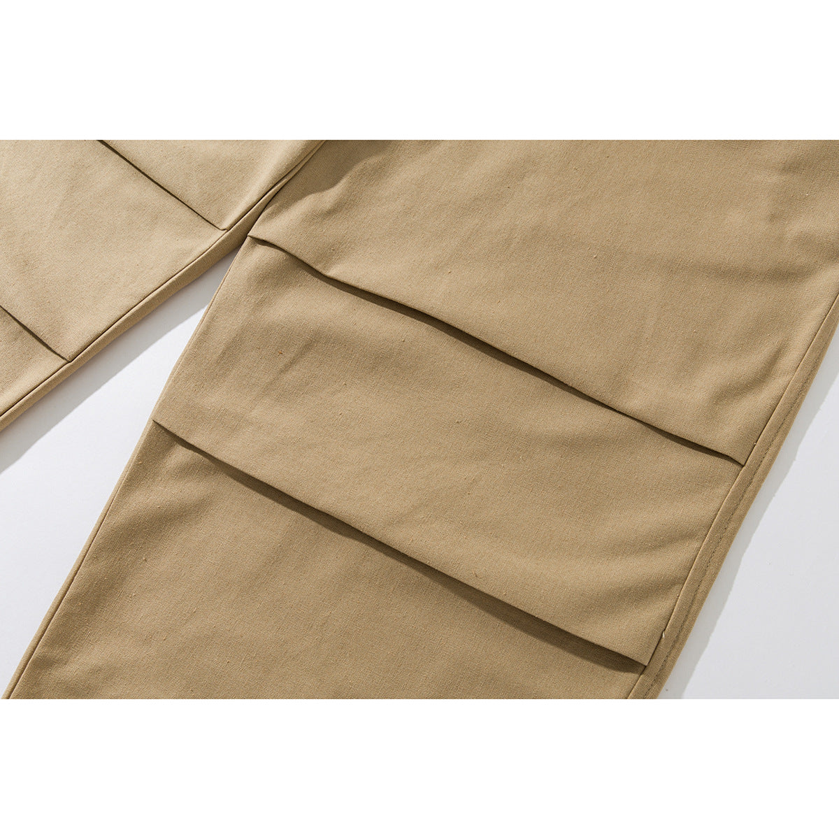 Close-up of tan pants showing layered horizontal panel seams and the fabric surface.