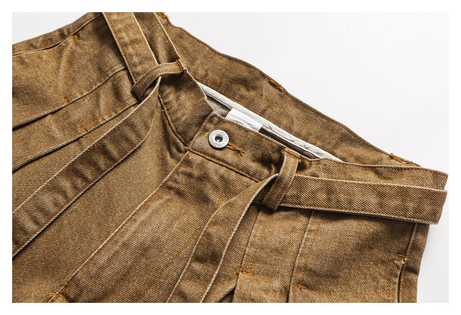 Close-up of tan trousers showing the waistband, button, belt loops, and pleated front.
