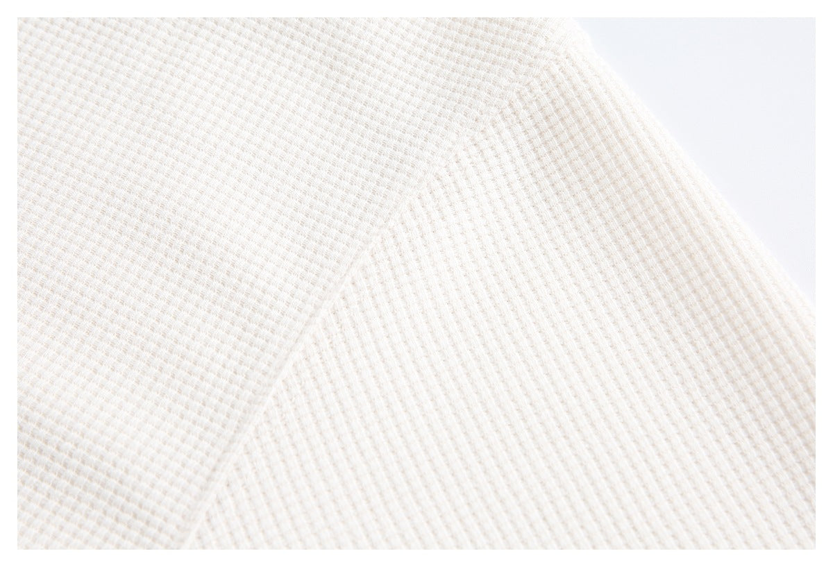Close-up of the off-white garment's small waffle-textured knit surface.