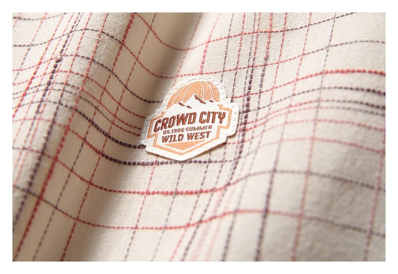 Close-up of an embroidered orange-and-white badge on beige fabric with red and gray plaid checks.