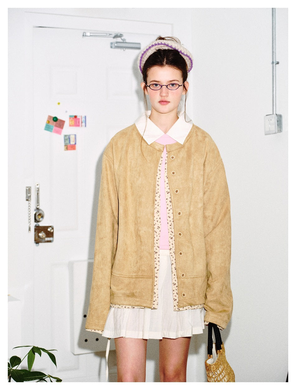 Model wearing a tan button-front jacket with cream floral trim over a pink top and white skirt.