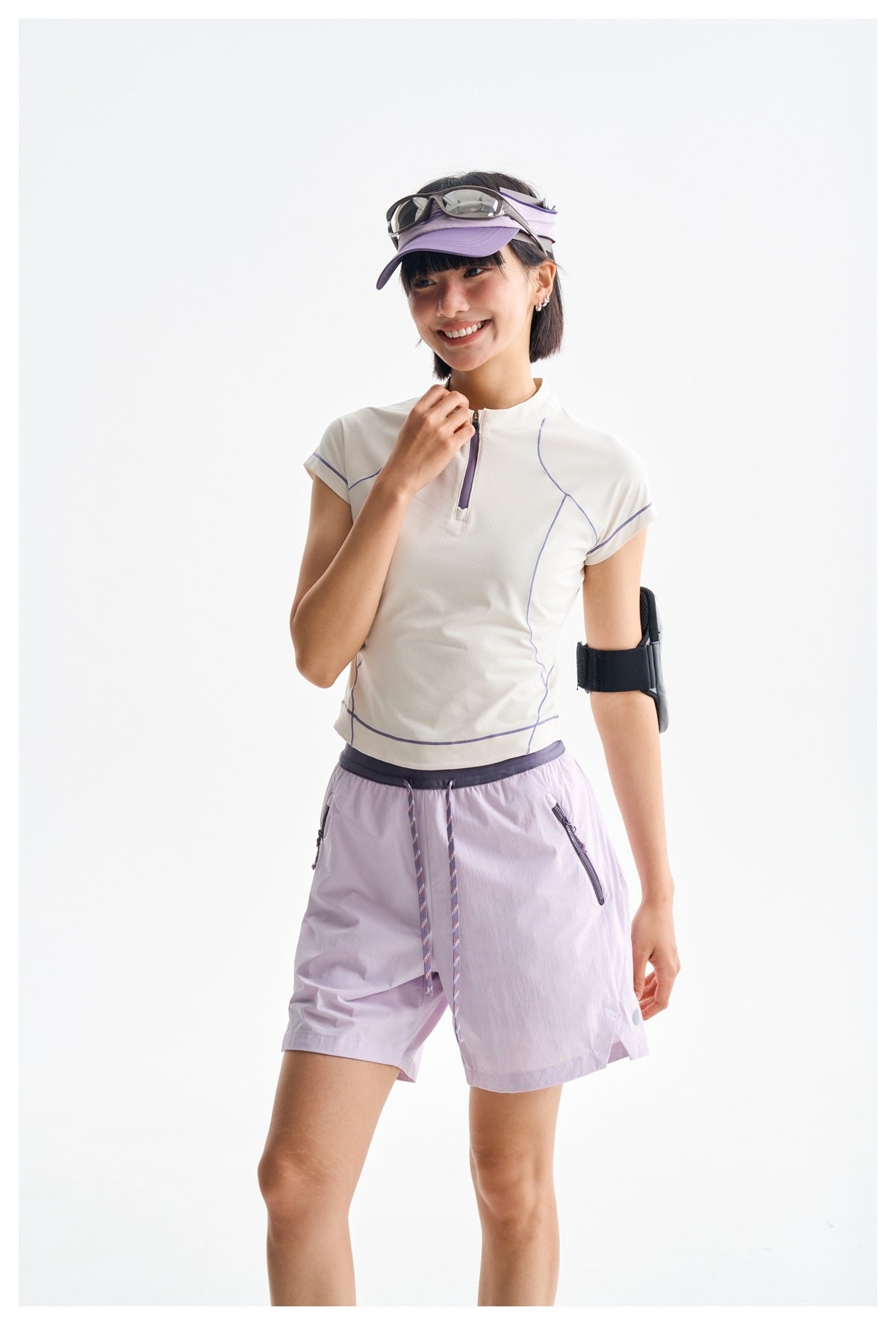 Model wearing a white zip-neck top with lavender piping and pale lavender shorts, shown at a slight angle.