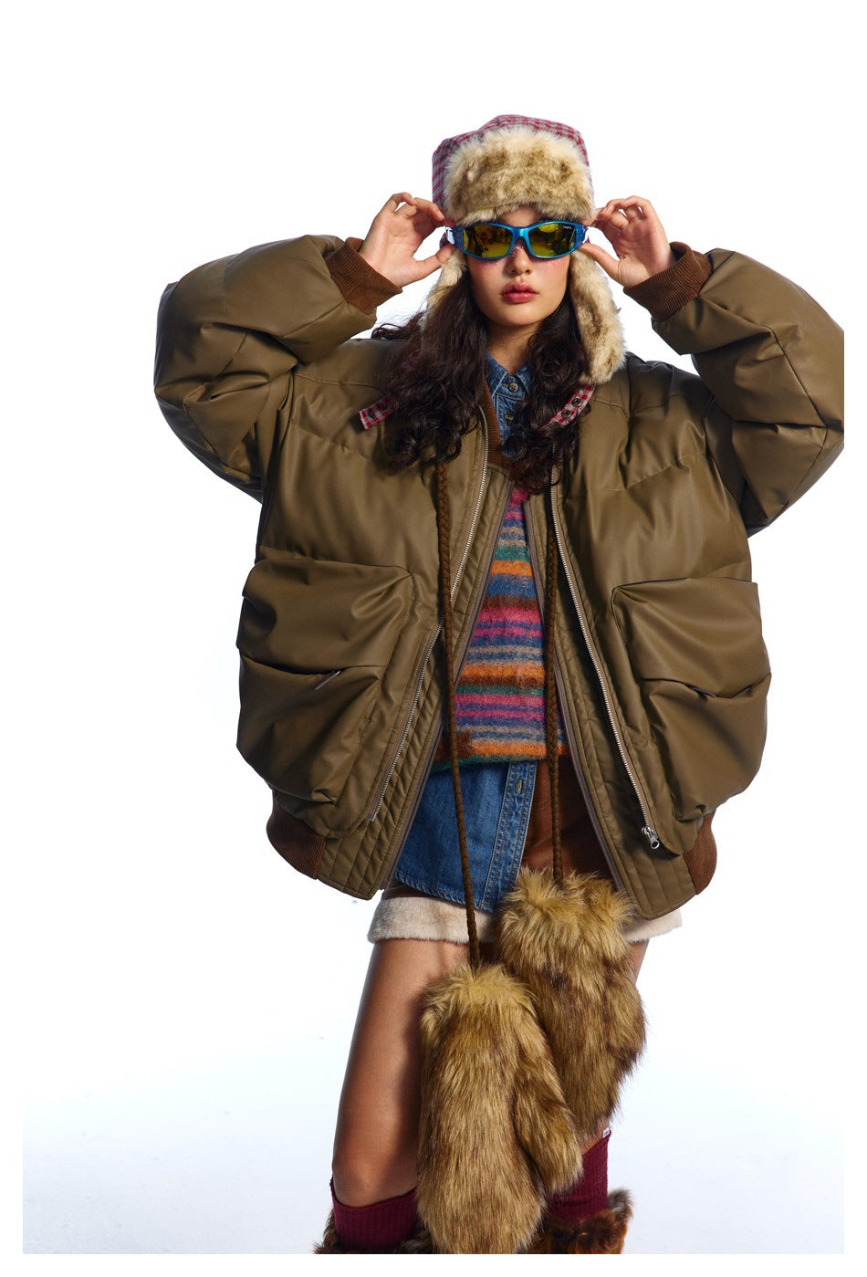 Front view of a model wearing an oversized olive-brown padded bomber jacket with large pockets and brown ribbed trim.