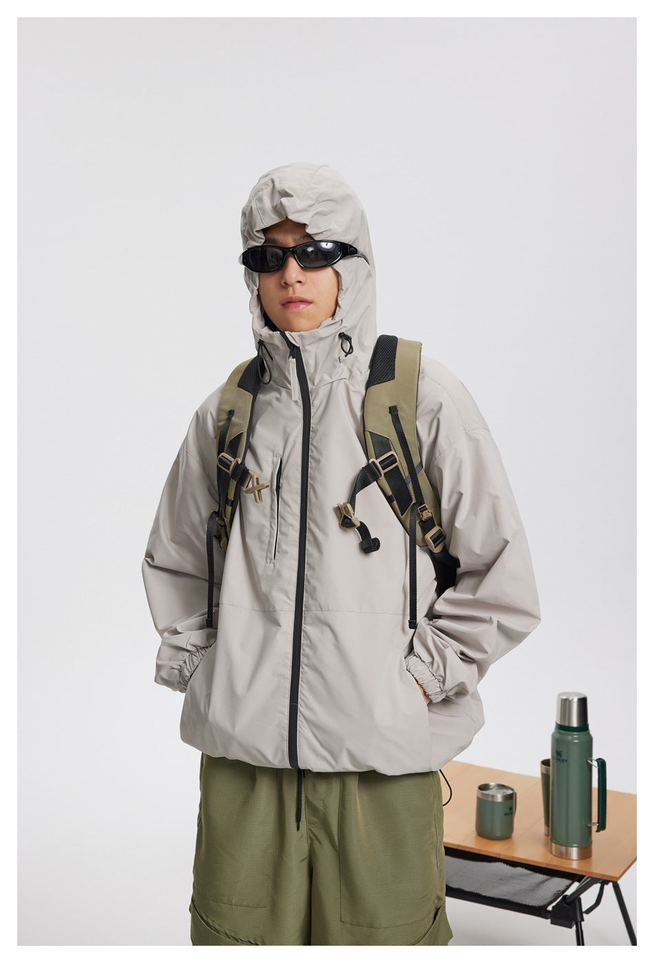 Front view of a person wearing a light gray hooded jacket, with the hood up.