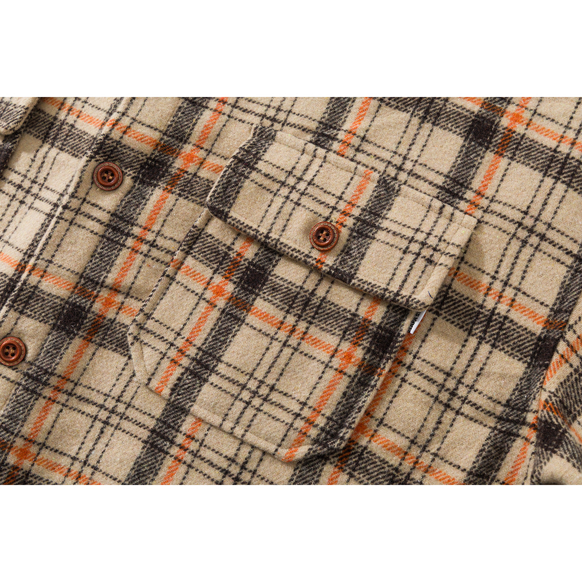 Close-up of a beige, black, and orange plaid shirt front showing a buttoned chest pocket.