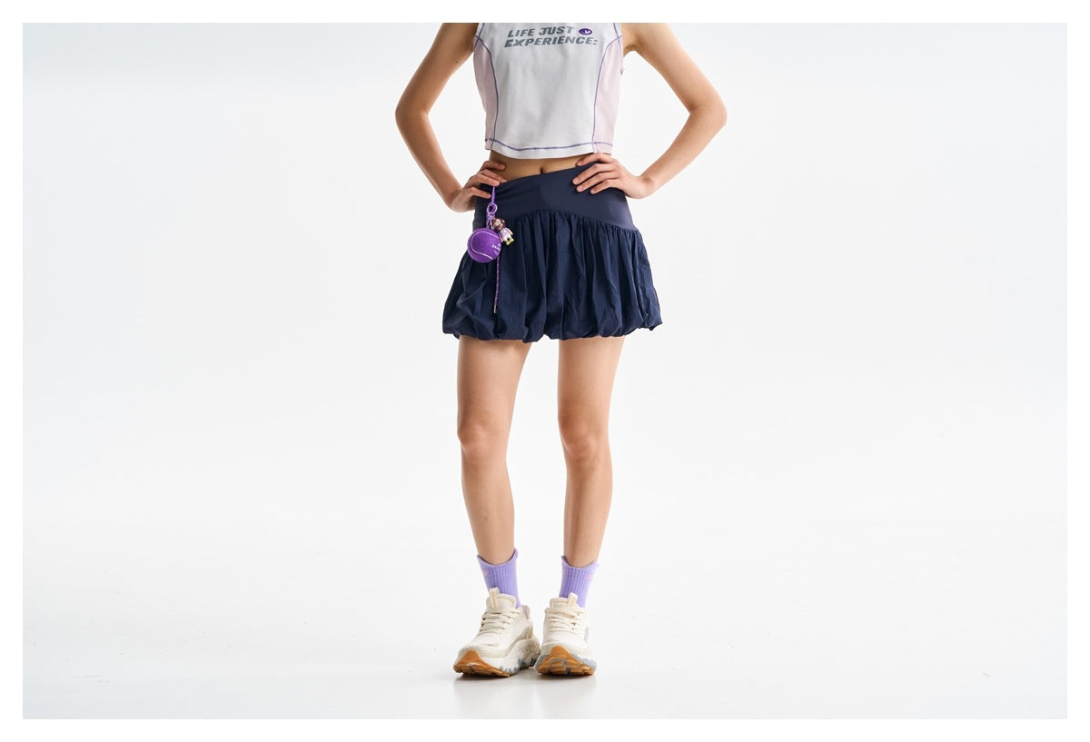 Cropped view of a model wearing a navy bubble skirt with a wide waistband, a pink crop top and lavender socks.