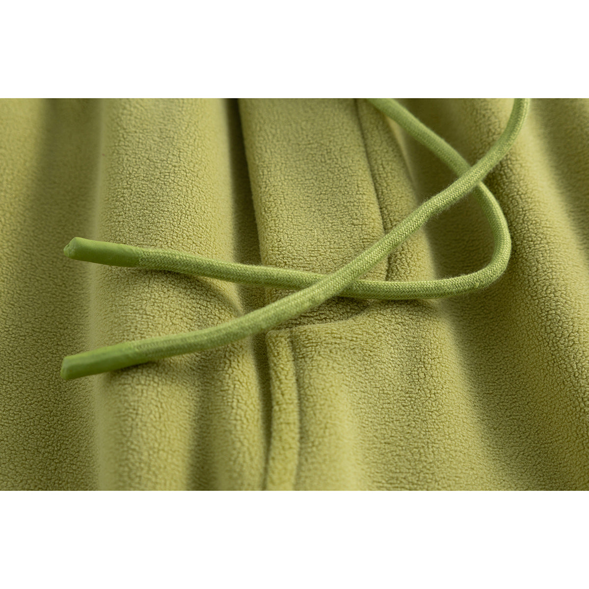 Close-up of olive green pants with braided drawstrings and a soft, textured surface.
