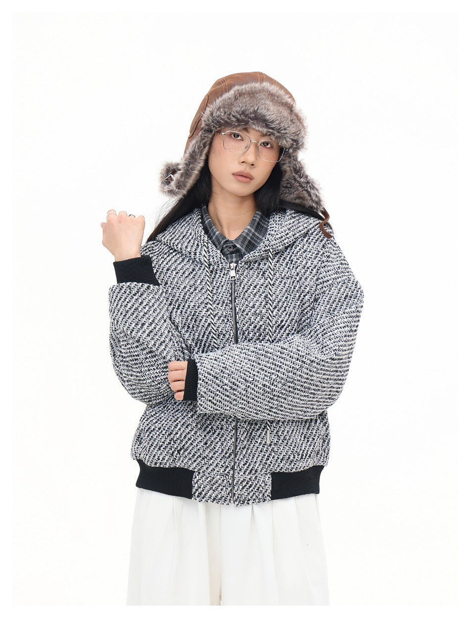 Model wearing a black-and-white patterned zip-up hooded jacket with black ribbed cuffs and hem; brown fur hat.