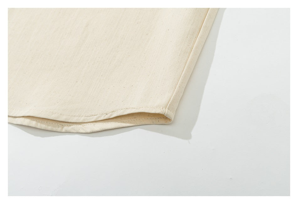 Close-up of the curved hem and stitched edge of a cream garment.