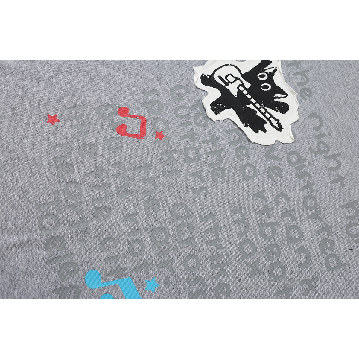Close-up of a gray shirt's printed text and music graphics, with a black-and-white guitar illustration.