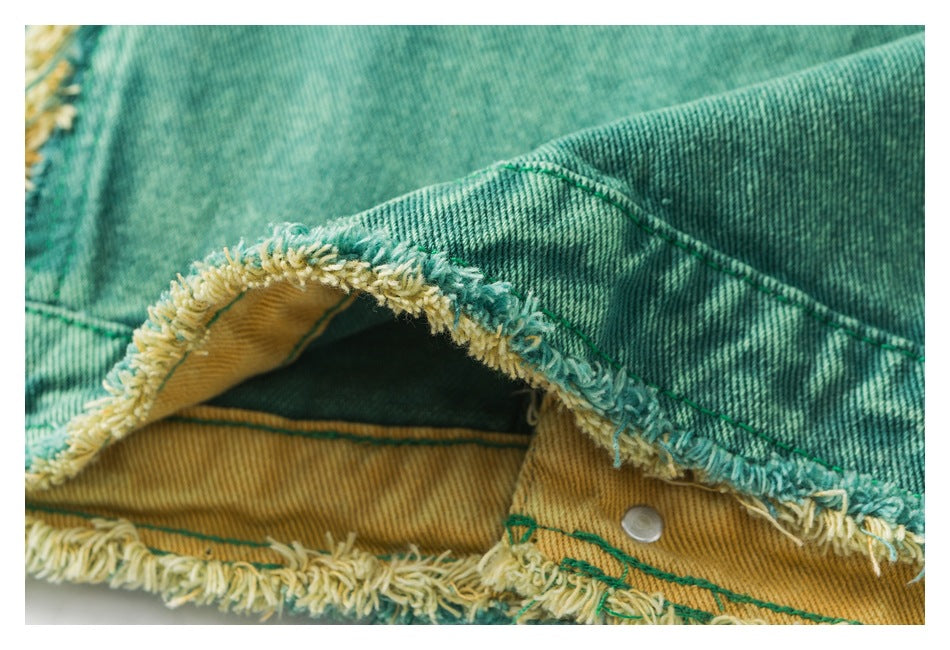 Close-up of an open teal denim edge showing yellow-and-teal fraying, mustard-colored inner fabric, and a metal snap.