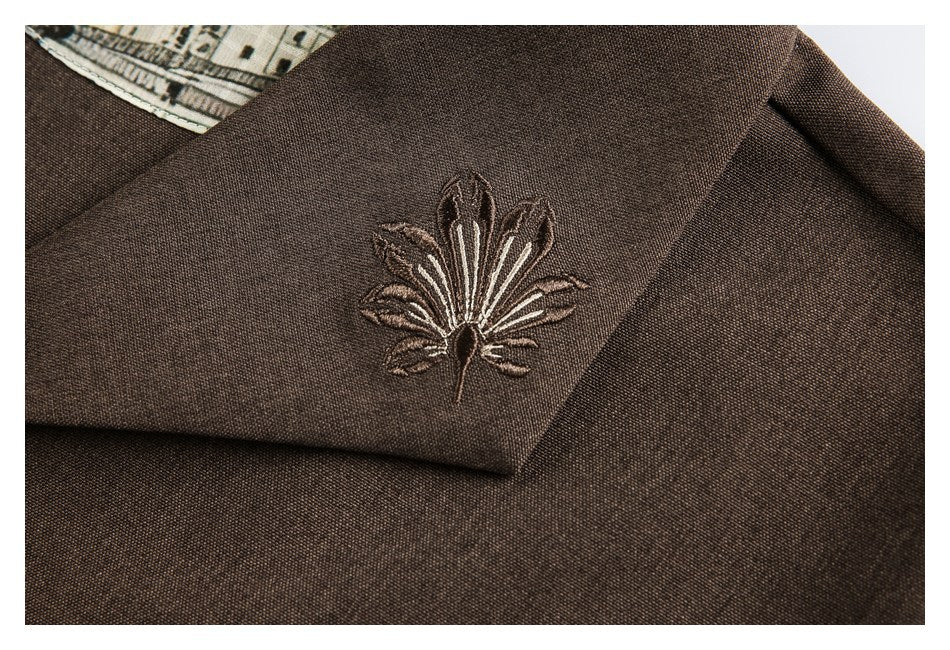 Close-up of a floral embroidered motif on the brown garment's collar.