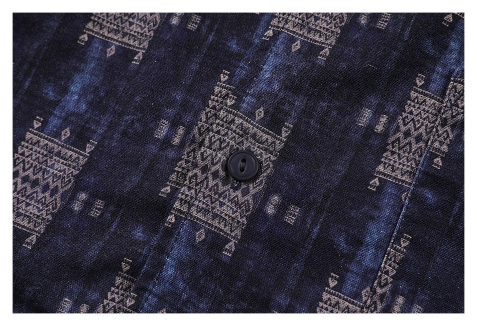 Close-up of a black button on dark navy fabric with muted geometric motifs.