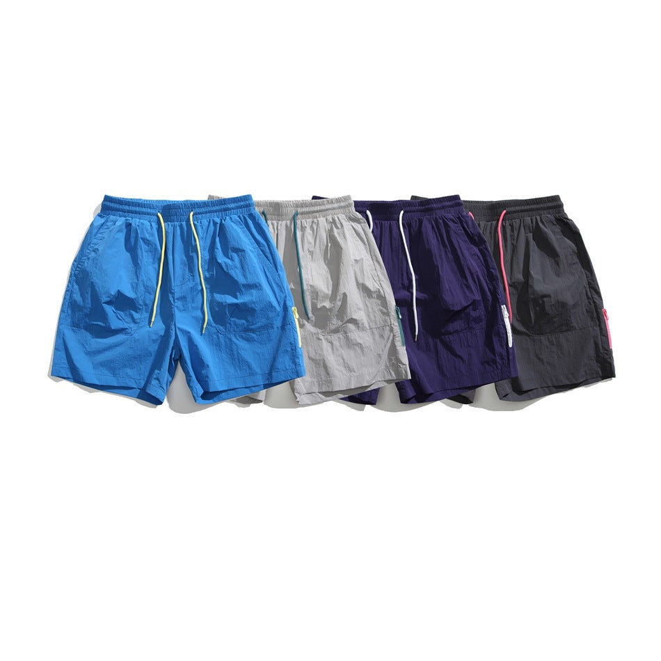 Four pairs of elastic-waist shorts shown together in blue, light gray, dark purple, and charcoal.