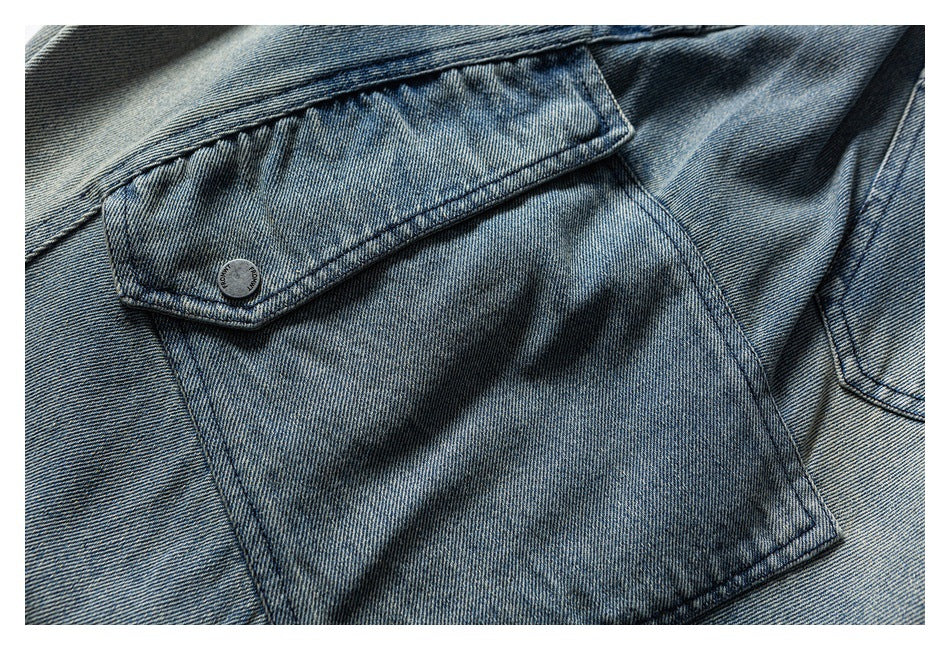 Close-up of a blue denim flap pocket secured with a dark button.