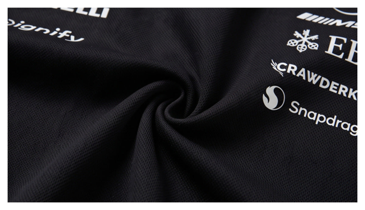 Close-up of black textured fabric gathered into folds, with white sponsor-style logos printed on it.