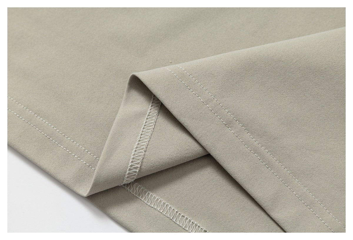 Close-up of taupe-gray garment fabric showing a double-stitched hem and overlocked seam.