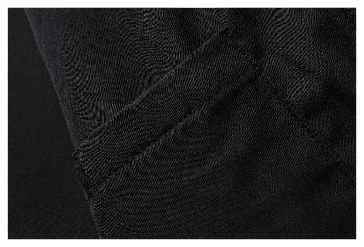 Close-up of black garment fabric showing a stitched seam and folded edge.