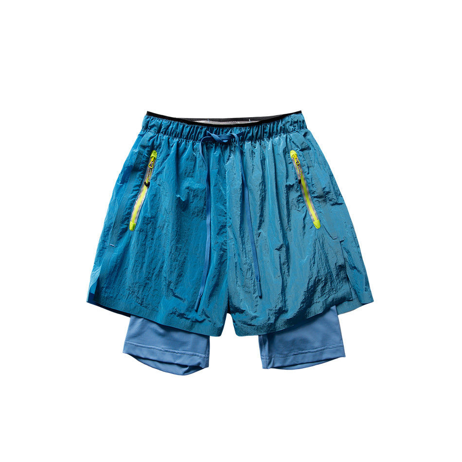 Blue double-layer athletic shorts with drawstring waist, neon yellow-green zippered pockets and a lighter blue inner layer