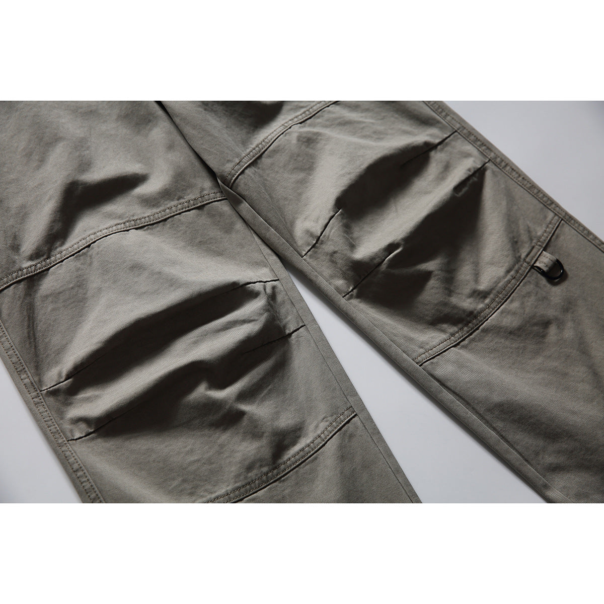 Close-up of gray work pants showing reinforced knee panels and a small side loop.