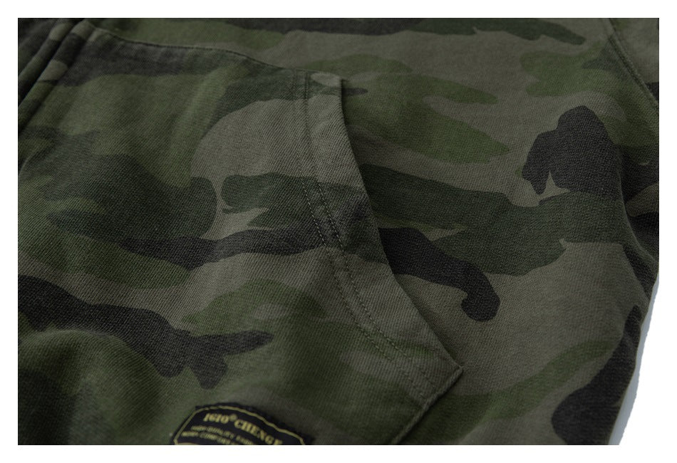 Close-up of a kangaroo pocket and small sewn label on an olive and black camouflage hoodie.