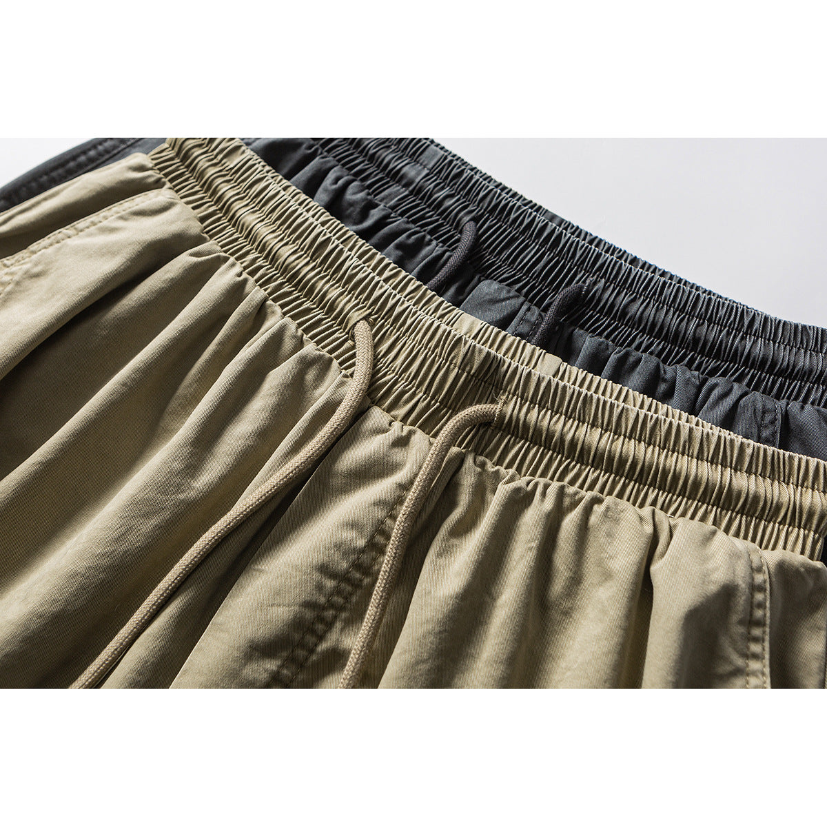 Close-up of khaki and charcoal shorts showing gathered elastic waistbands and matching drawstrings.