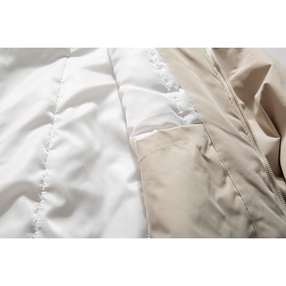 Close-up of the jacket's white quilted lining beside the beige outer fabric and zipper.