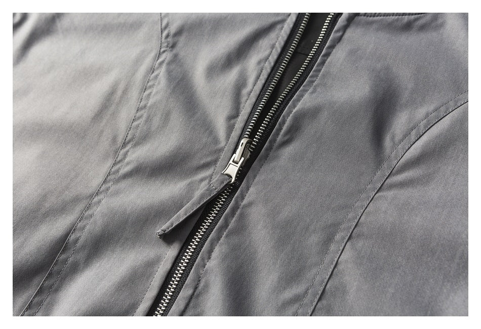 Close-up of a metal front zipper and curved seam on a gray jacket.