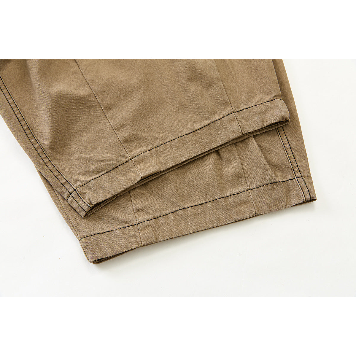 Close-up of the tan pants' wide leg hems with dark contrast stitching.