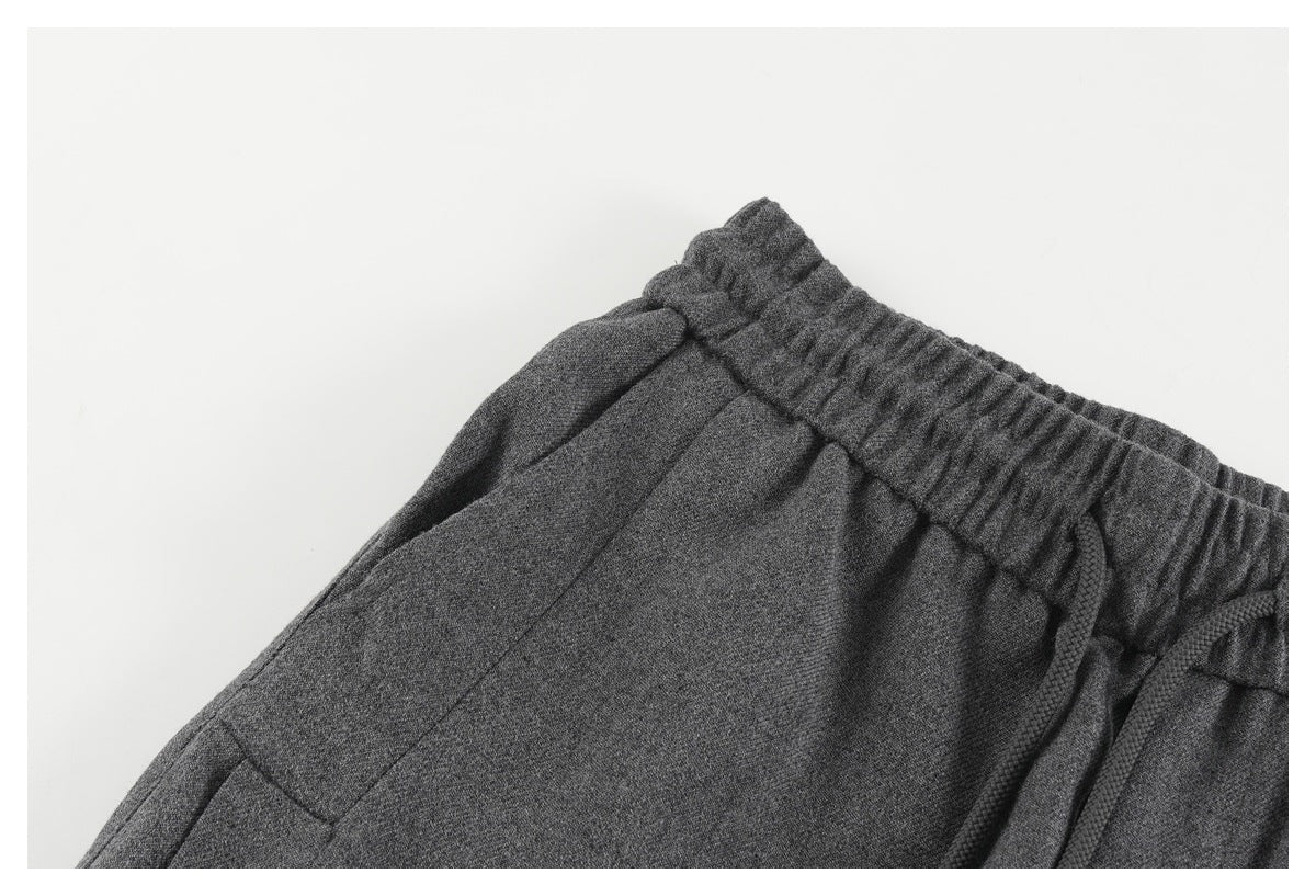 Close-up of charcoal gray pants showing the gathered elastic waist, drawstring, and side pocket seam.