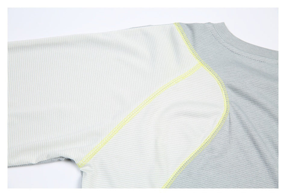 Close-up of a light gray and white shirt with curved neon-yellow overlock stitching at the sleeve and underarm.