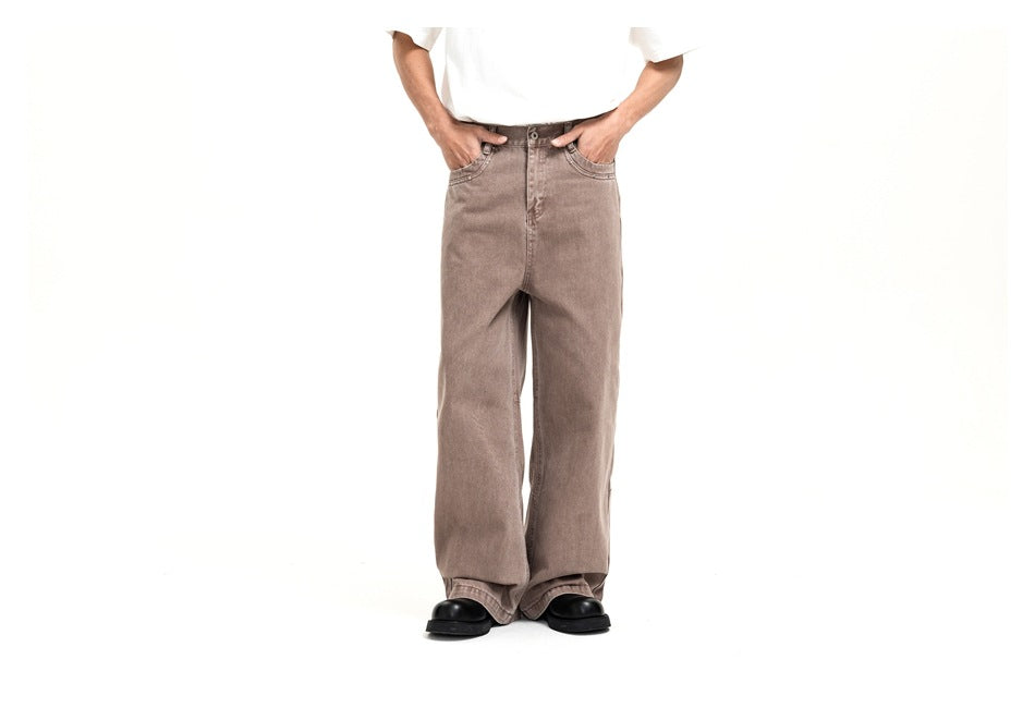 Front view of a model wearing loose taupe jeans with a button fly, curved front pockets and wide legs.