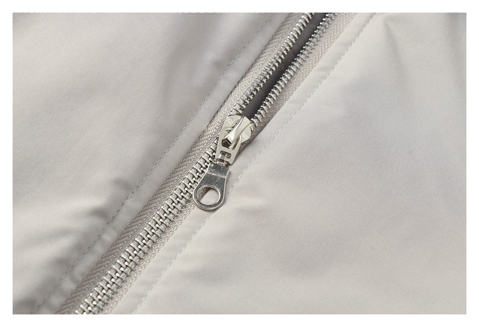 Close-up of the silver zipper and pull on a light gray jacket.