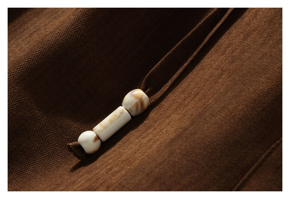 Detail of a pale, marbled bead cord end against the brown trouser fabric.