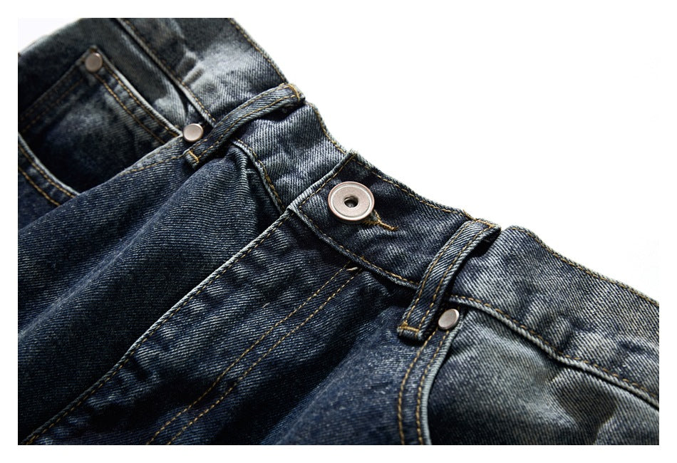 Close-up of the button, belt loop and fly stitching on dark washed blue jeans.