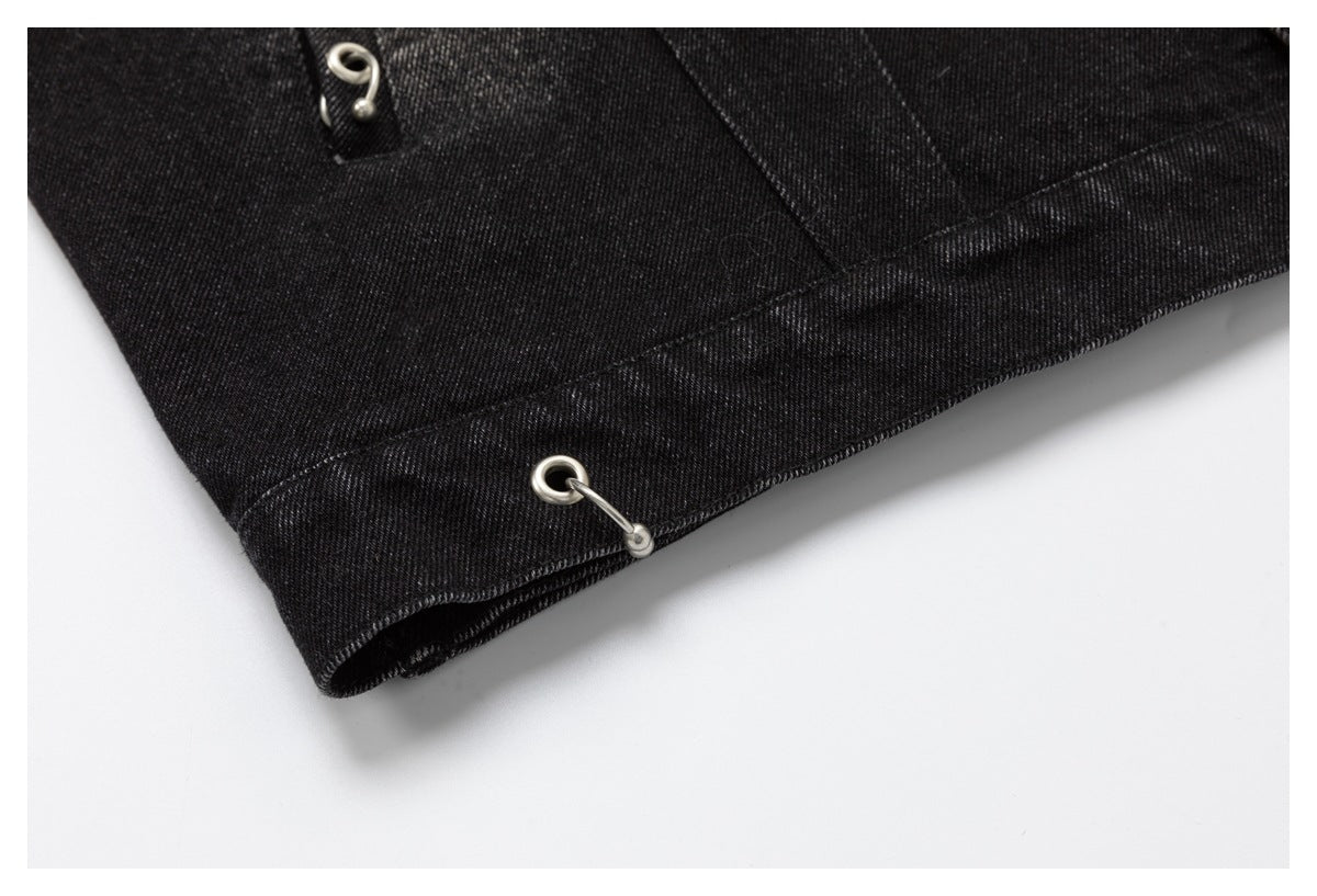 Close-up of a black denim hem with a metal eyelet and hook fastening.